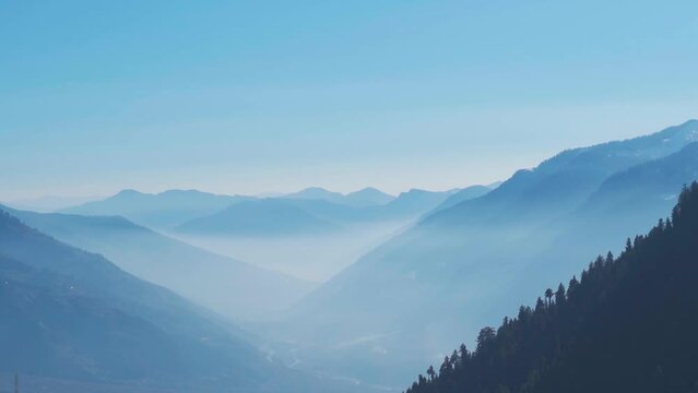 Foggy mountain layers as seen from above the mountains during the Rani Sui Trek near Manali in Himachal Pradesh, India. Natural mountain background. Himalayas covered by the fog during the morning. 