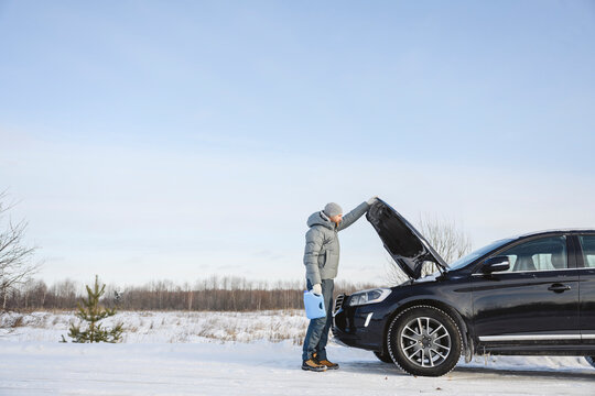 Man with anti-freeze liquid opening car hood on winter road