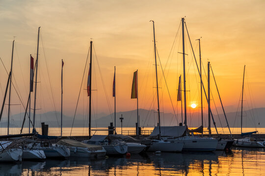 Italy, Veneto, Bardolino, Sailboats moored in harbor at sunset