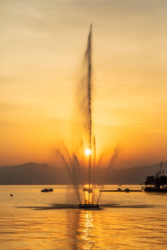 Italy, Veneto, Bardolino, LakeGardafountain splashing against setting sun