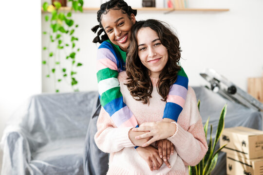 Smiling young woman embracing friend at home