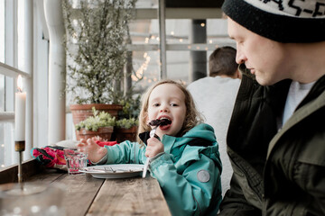 father and daughter eating chocolate cake in a cafe together