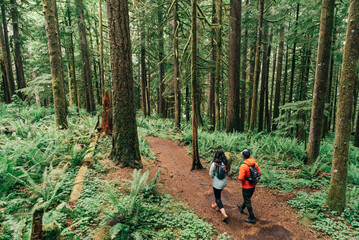 A young couple enjoys a hike in a forest in the Pacific Northwest.