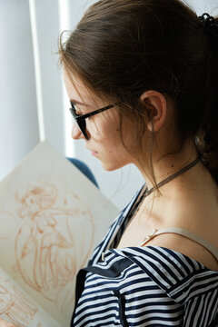 millennial girl draws fabulous images on paper while sitting at home