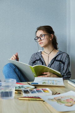 millennial girl draws fabulous images on paper while sitting at home