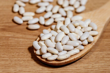 Fototapeta na wymiar White beans in a wooden spoon on a wooden table