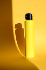Yellow spray can on a black background. No inscriptions. Yellow spray. Hair care cosmetics
