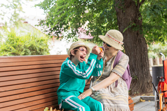 Daughter with disability enjoying by mother sitting on bench