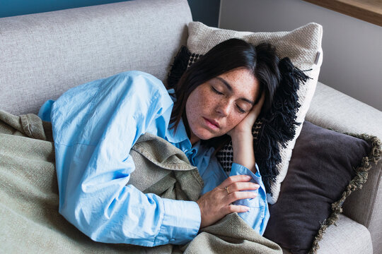 Young woman with eyes closed resting on sofa at home