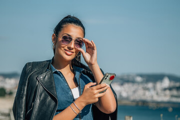 young latin hispanic woman walking along the promenade with phone