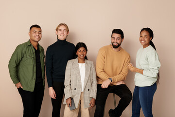 Smiling multiracial business colleagues posing against beige background