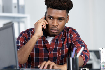 concentrated young man with phone at an office desk