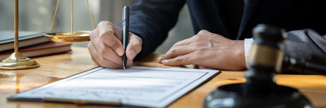 Young Asian lawyer or legal advisor reading clarification on business agreement with the signing of the investment contract according to the laws and regulations in the office.