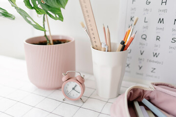 School supplies and alarm clock on table at home