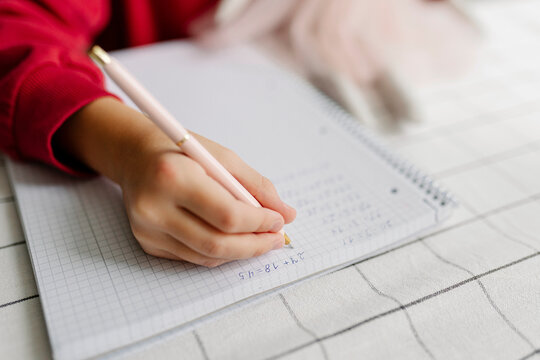 Hands of girl doing math homework at home