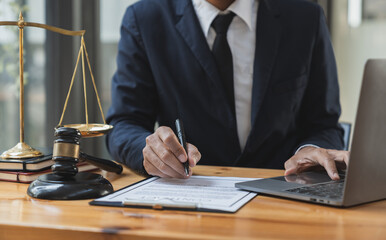 Young Asian legal advisor or lawyer sits on a laptop and compares data analyzing business deals on...