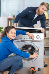 young happy womanand man fixing washer in kitchen