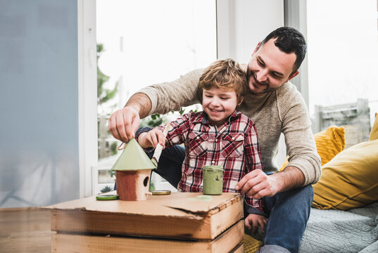 Happy father and son painting model house at home