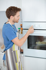 man cooking something in the oven in home kitchen