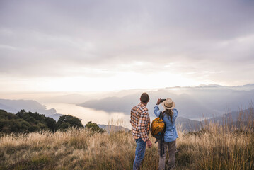 Mature man with woman photographing through smart phone