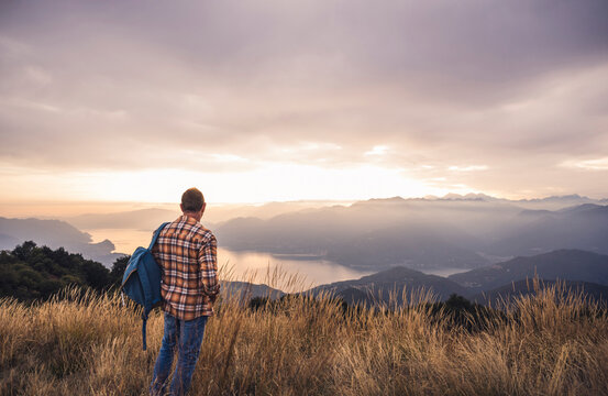 Mature man with backpack standing on mountain at sunset - Powered by Adobe