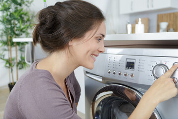 smiling woman pressing button on modern washing machine