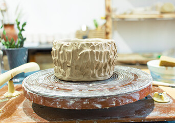 Bowl of handmade light clay on a potter's wheel in a pottery workshop. Close up
