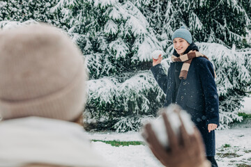 Boyfriend and girlfriend playing with snowballs in park