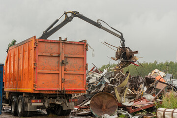 Loading of scrap metal by hydraulic crane, for recycling.