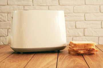 Modern electric toaster and a stack of fresh fried bread slices on the wooden table. Cooking and homeware technologies backgrounds