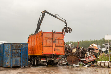 Loading of scrap metal by hydraulic crane, for recycling.