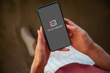 Woman holding smartphone got a message on screen phone with grey background