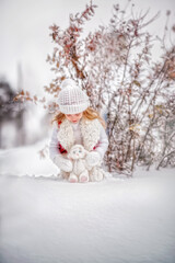 Beautiful little girl with long hair. Little girl in the winter forest. girl in a hat. Girl in a Zara sheepskin coat. A little girl hugs a toy hare. Winter. Snow. Tender baby. Baby girl portrait
Toy B