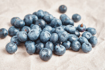 Fresh blueberries scattered on beige craft paper.