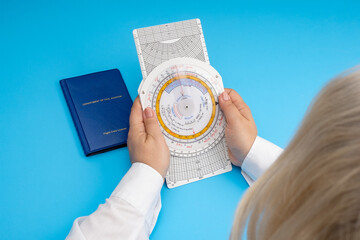 A female student pilot holds a navigation computer in her hands. Woman's aspiration to become an airline pilot