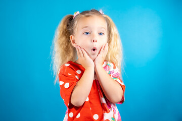 A cute girl in a red polka dot dress expresses extreme amazement and surprise