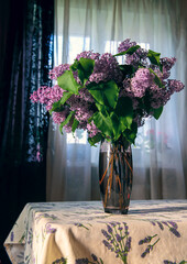 A close-up image of a vase with lilacs. Home interior with a bouquet of blooming lilac flowers on...
