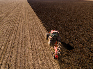 Farmer in tractor cultivating stubble field in preparation for crop planting