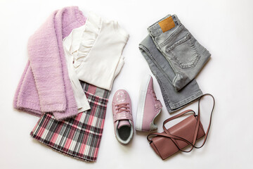 8 year old Girl clothes set, white blouse, grey geans and plaid skirt, pink sneakers, small  bag on white background.