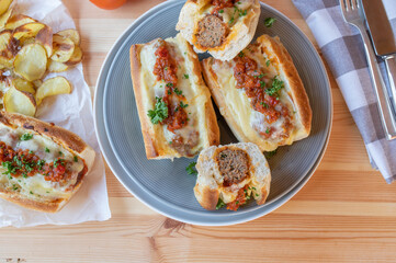 Italian Meatball sandwiches or subs with cheese and homemade potato chips on a  dinner table. Flat...
