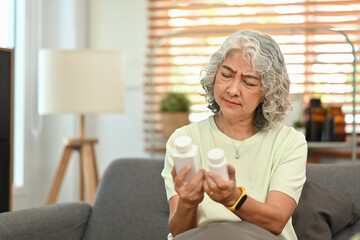 Confused middle age lady reading medicine instruction on packaging before take meds. Elderly healthcare concept