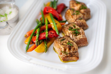 Black Cod on serving platter with grilled vegetables and rice.