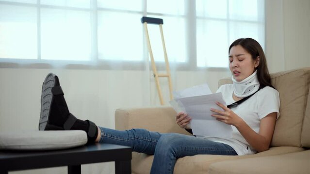 UnHappy woman stressed pay invoice medical expenses from accident fracture broken bone injury with leg splints in cast, neck splints collar, sling support arm. Social security and health insurance.