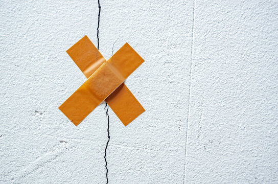 The band-aid plaster on a crack in the home wall. Cracks in the wall caused by ground shrinkage, the need to repair the building, renovation.