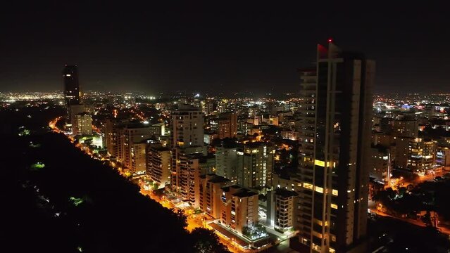 Residential Skyscraper And Modern Buildings Lit At Night Along Avenida Anacaona In Downtown Santo Domingo, Dominican Republic. aerial
