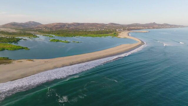 Scenic View Of Waves Crashing Along Shoreline in San Jos&eacute; del Cabo Next To San Jos&eacute; Estuary At Los Cabos, Baja California Sur, Mexico With Mountains in the distance. Aerial Tilt Down