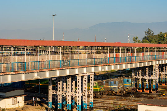 Railway foot over bridge to cross railway tracks at New Jalpaiguri Rail Station with Himalyan Range in background and few rail engine just bellow the over bridge.