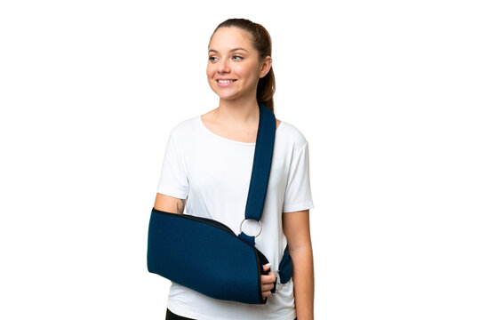 Young blonde woman with broken arm and wearing a sling over isolated chroma key background looking side