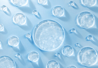 round drops of transparent gel serum on blue background 