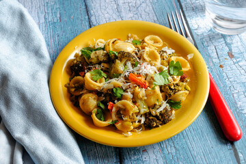 Italian pasta with broccoli, almonds and Parmesan. Served on yellow plate and blue wooden table.